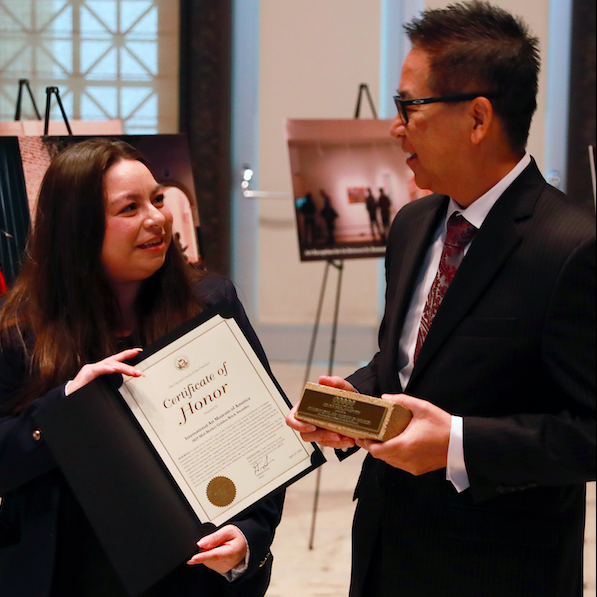 two people with award and docmuent